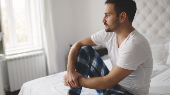 man-sitting-on-a-bed-looking-contemplative-suffering-from-erectile-dysfunction-or-ed